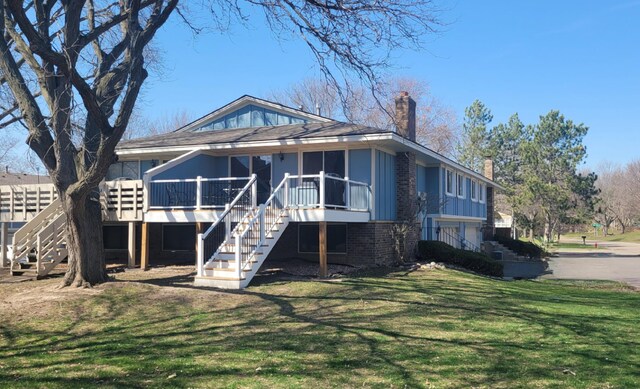 rear view of house with a sunroom, a yard, and a deck