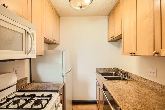 kitchen with white appliances, light brown cabinets, and sink