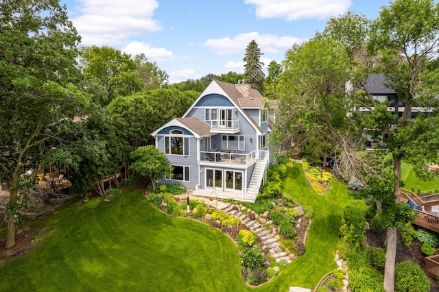 back of property with a balcony, stairs, and a yard