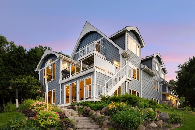 back of property at dusk with stairway and a balcony