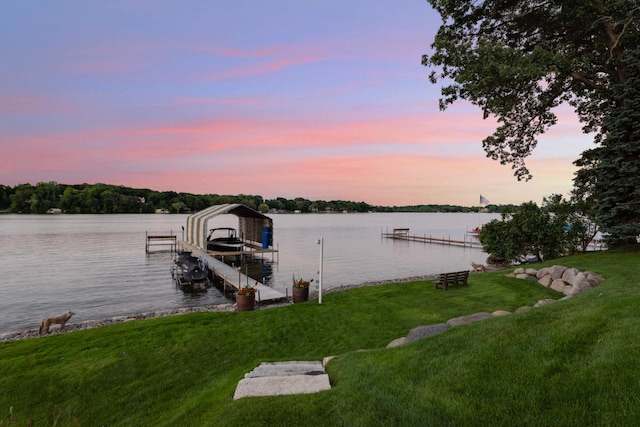 view of dock with a water view, boat lift, and a yard