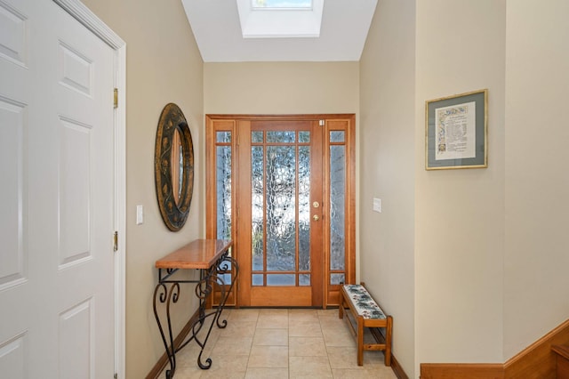 foyer entrance with a skylight, light tile patterned flooring, and baseboards