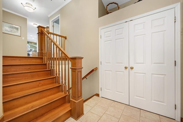 entrance foyer featuring light tile patterned floors, baseboards, stairs, and crown molding