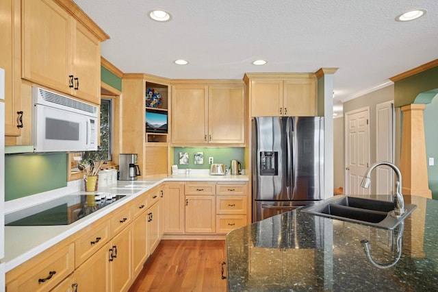 kitchen featuring white microwave, black electric cooktop, light brown cabinets, stainless steel refrigerator with ice dispenser, and a sink