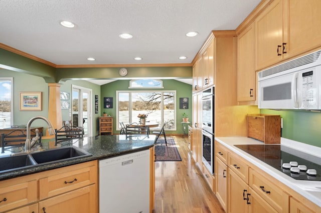 kitchen with white appliances, decorative columns, light brown cabinetry, light wood-style floors, and a sink