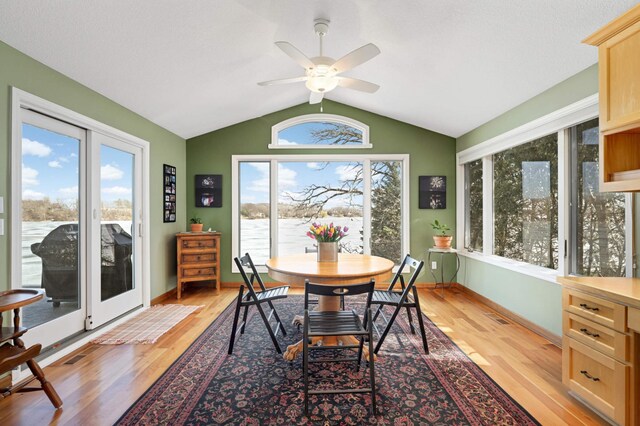 dining space featuring light wood finished floors, ceiling fan, baseboards, and vaulted ceiling