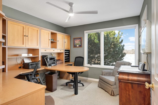 office area with a ceiling fan and baseboards