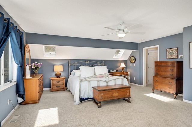 bedroom with ceiling fan, vaulted ceiling with skylight, carpet flooring, visible vents, and baseboards