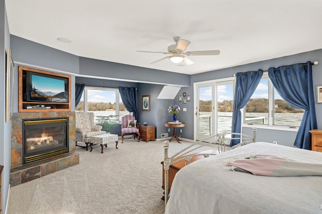 carpeted bedroom with baseboards, multiple windows, a tile fireplace, and access to exterior