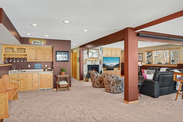 living area featuring indoor wet bar, recessed lighting, light carpet, and a stone fireplace