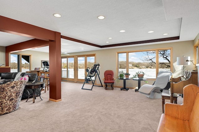 interior space with a textured ceiling, recessed lighting, carpet floors, baseboards, and a raised ceiling