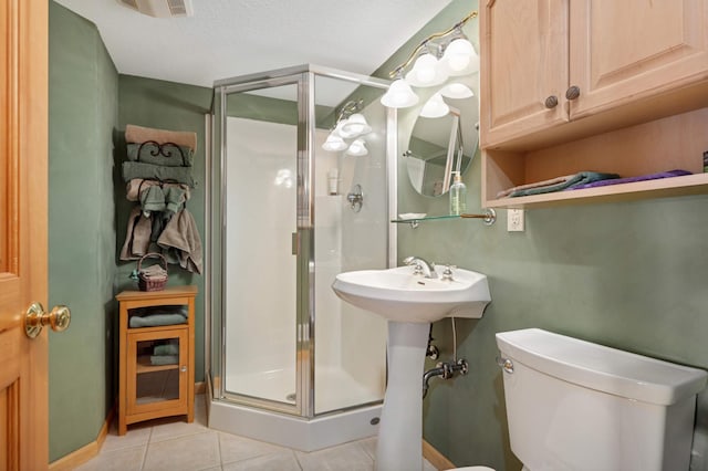 bathroom featuring a textured ceiling, tile patterned flooring, toilet, and a shower stall