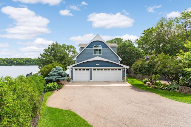 garage with driveway, a water view, and fence