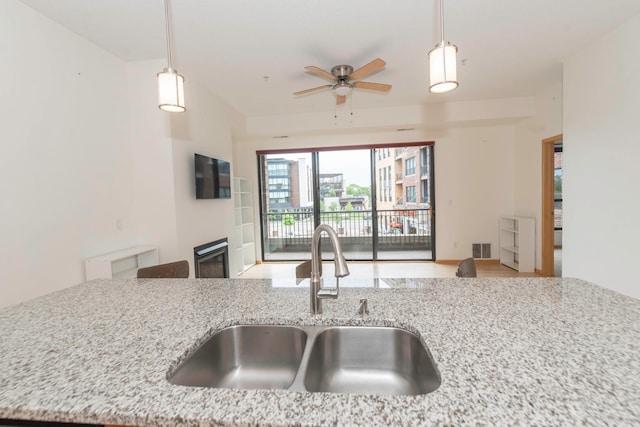 kitchen with sink, decorative light fixtures, light stone countertops, and ceiling fan