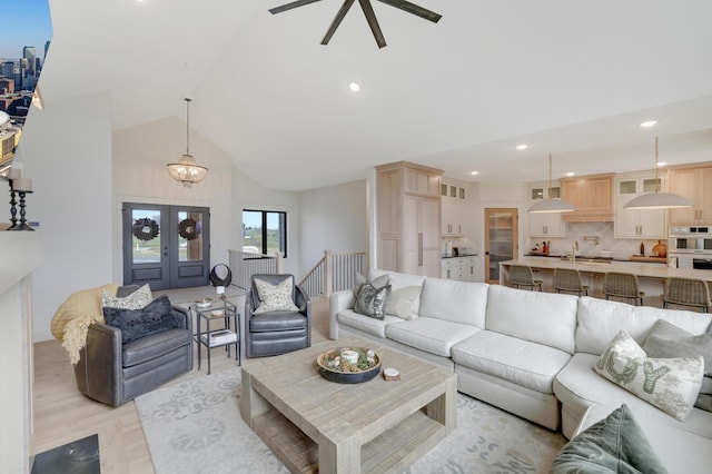 living room featuring light hardwood / wood-style flooring, high vaulted ceiling, french doors, and a notable chandelier