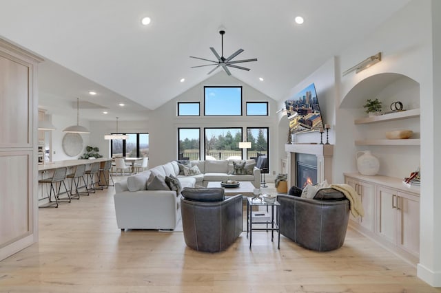 living room featuring ceiling fan, high vaulted ceiling, and light wood-type flooring