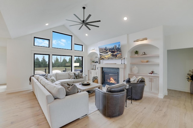 living room with ceiling fan, built in features, high vaulted ceiling, and light hardwood / wood-style flooring