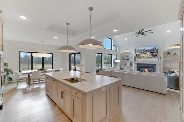 kitchen with a wealth of natural light, decorative light fixtures, a kitchen island with sink, and sink