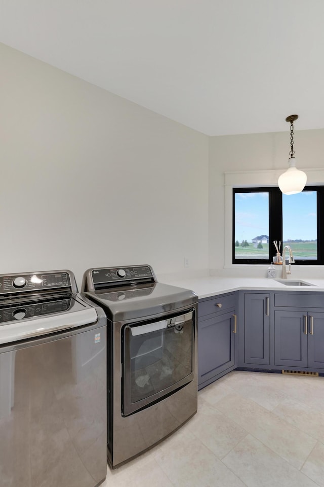 clothes washing area featuring washer and dryer, sink, light tile patterned floors, and cabinets