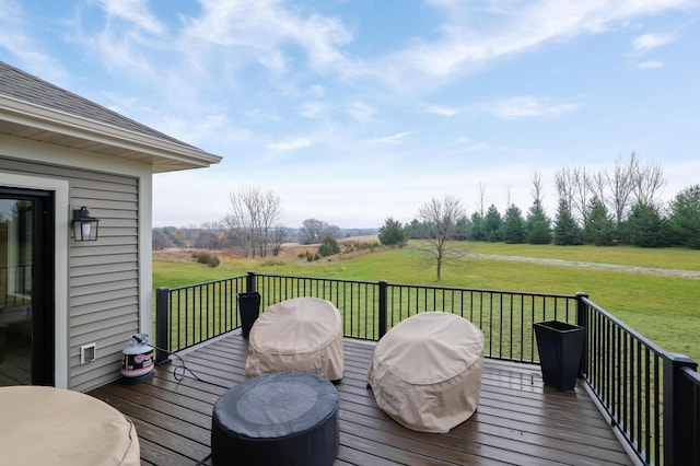 wooden terrace featuring a lawn and a rural view