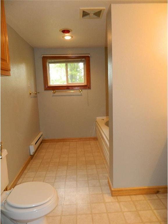 bathroom with a baseboard heating unit, tile flooring, and toilet