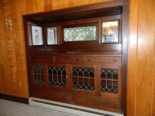 interior details with a baseboard heating unit, wood walls, and carpet flooring