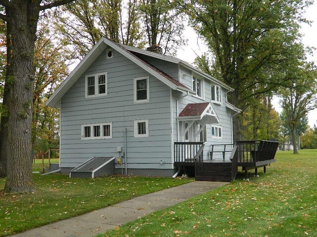 back of property with a deck and a lawn