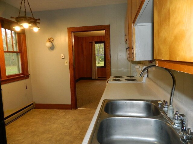 kitchen featuring pendant lighting, stove, baseboard heating, light tile floors, and sink