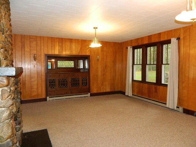 unfurnished living room featuring wooden walls, a baseboard radiator, carpet floors, and a fireplace