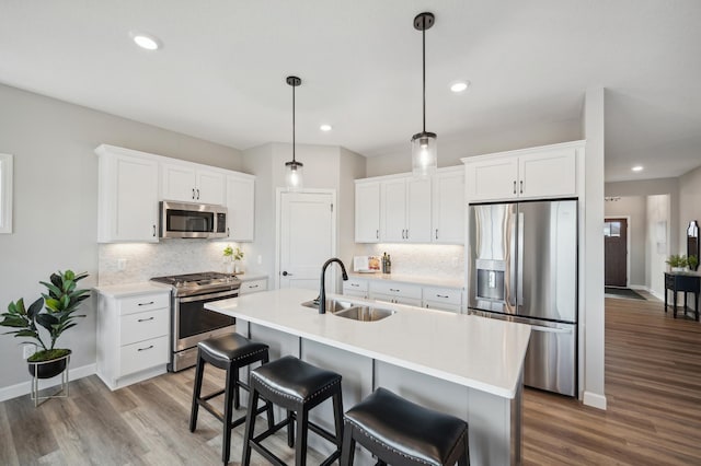 kitchen featuring white cabinets, a center island with sink, sink, light hardwood / wood-style flooring, and appliances with stainless steel finishes