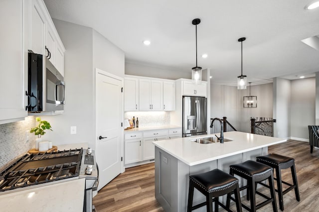 kitchen featuring dark wood-type flooring, white cabinets, sink, an island with sink, and appliances with stainless steel finishes