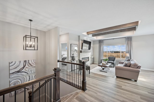 living room with light hardwood / wood-style floors, a fireplace, and an inviting chandelier