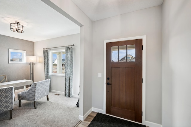 entryway featuring carpet, a textured ceiling, an inviting chandelier, and plenty of natural light