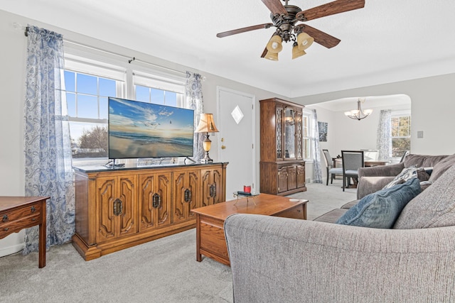 living room with ceiling fan with notable chandelier and light carpet