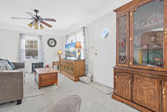 carpeted living area featuring a ceiling fan, a wealth of natural light, and a textured ceiling