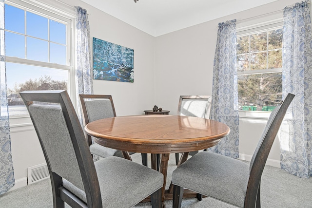 carpeted dining space featuring visible vents