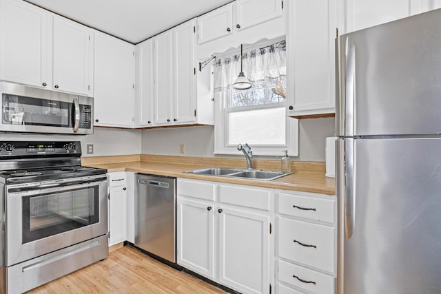 kitchen featuring a sink, stainless steel appliances, white cabinetry, and light countertops