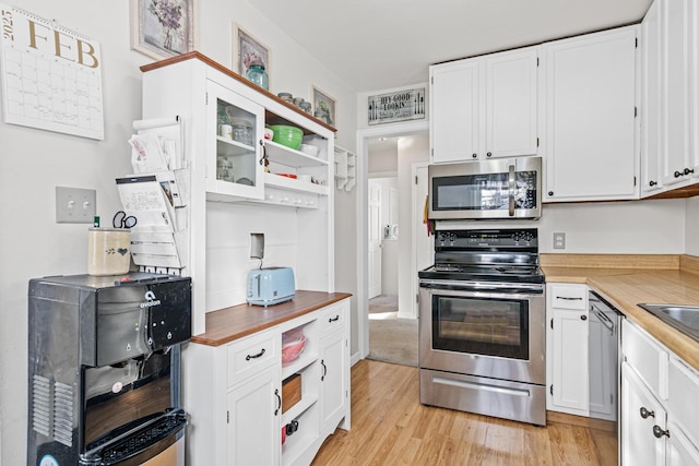 kitchen featuring open shelves, light wood-type flooring, appliances with stainless steel finishes, and white cabinetry