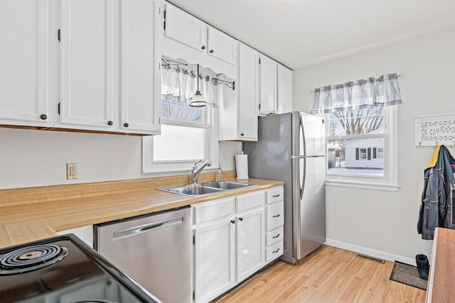 kitchen with visible vents, light wood-style flooring, a sink, white cabinetry, and stainless steel appliances