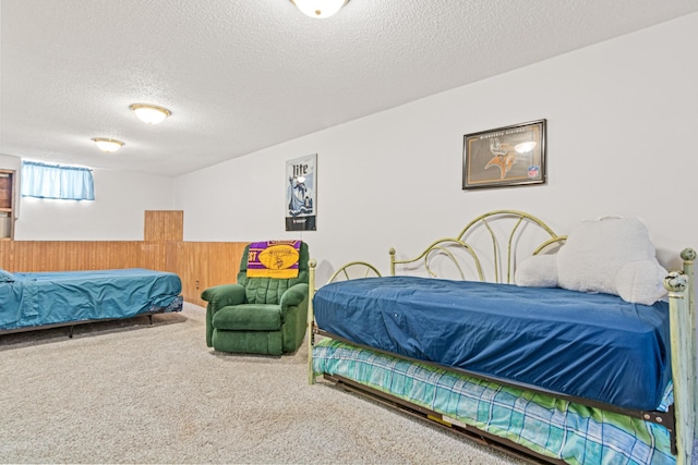 bedroom featuring a wainscoted wall, a textured ceiling, wood walls, and carpet flooring