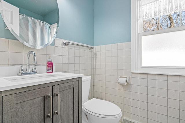 bathroom featuring vanity, tile walls, and toilet