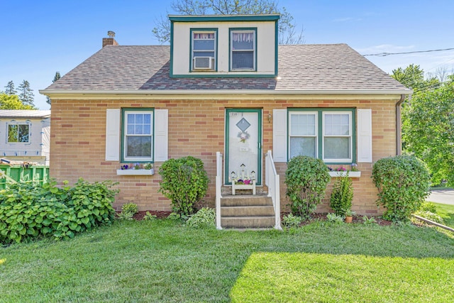 bungalow-style house with a front lawn, brick siding, and a shingled roof