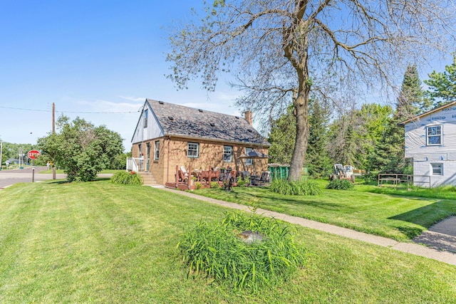 exterior space with brick siding, a front yard, and a chimney