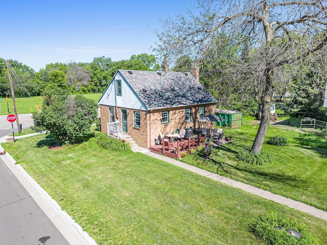 view of front of home with brick siding, a chimney, and a front lawn