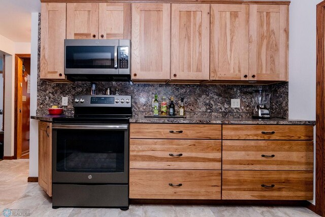 kitchen featuring decorative backsplash, dark stone counters, light brown cabinetry, and appliances with stainless steel finishes