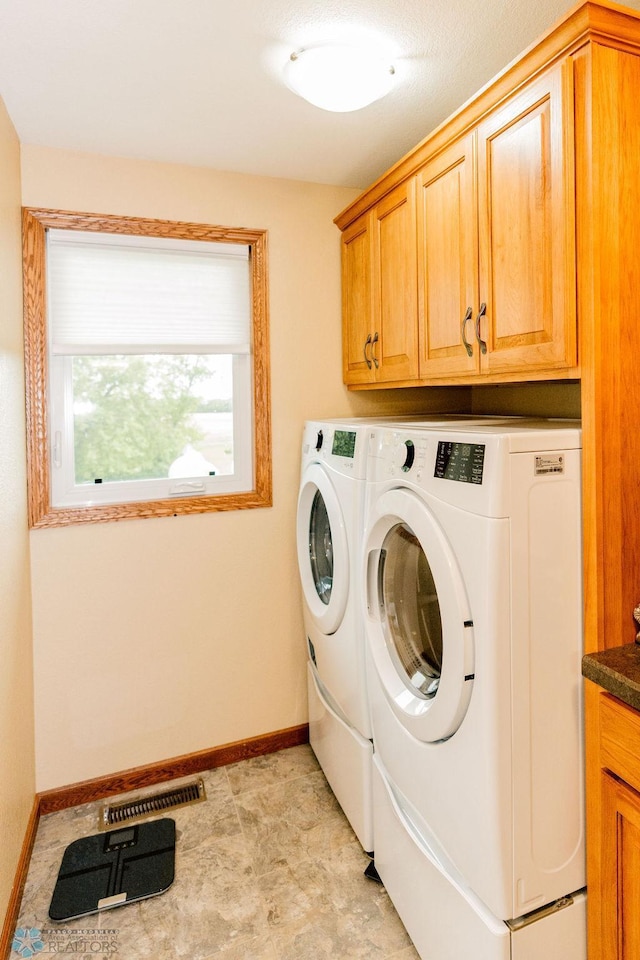 washroom featuring washer and clothes dryer, cabinets, and light tile floors