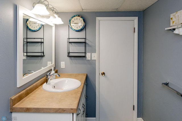 bathroom featuring vanity with extensive cabinet space and a drop ceiling