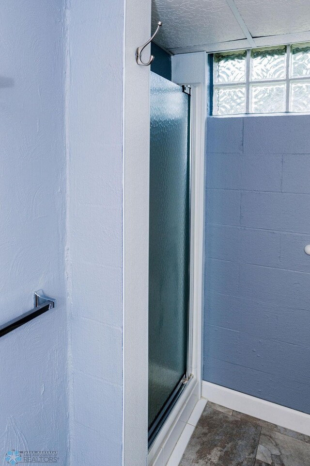 full bath featuring baseboards, a textured ceiling, and a shower stall