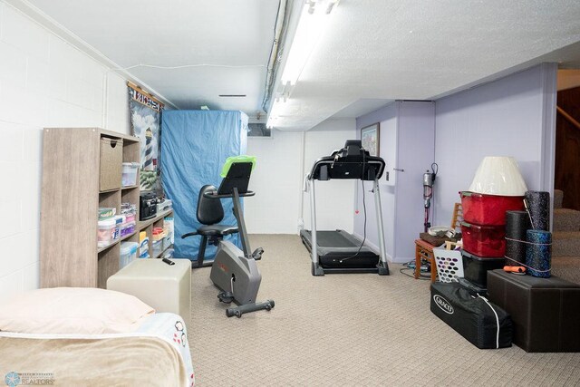 workout area featuring concrete block wall and carpet
