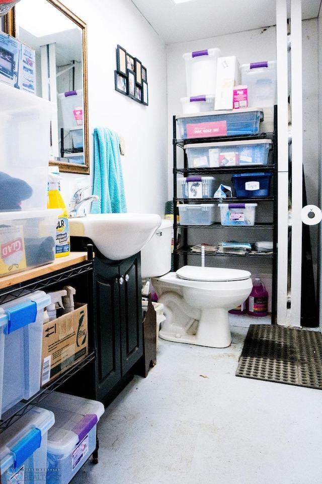 bathroom with concrete floors, toilet, and vanity